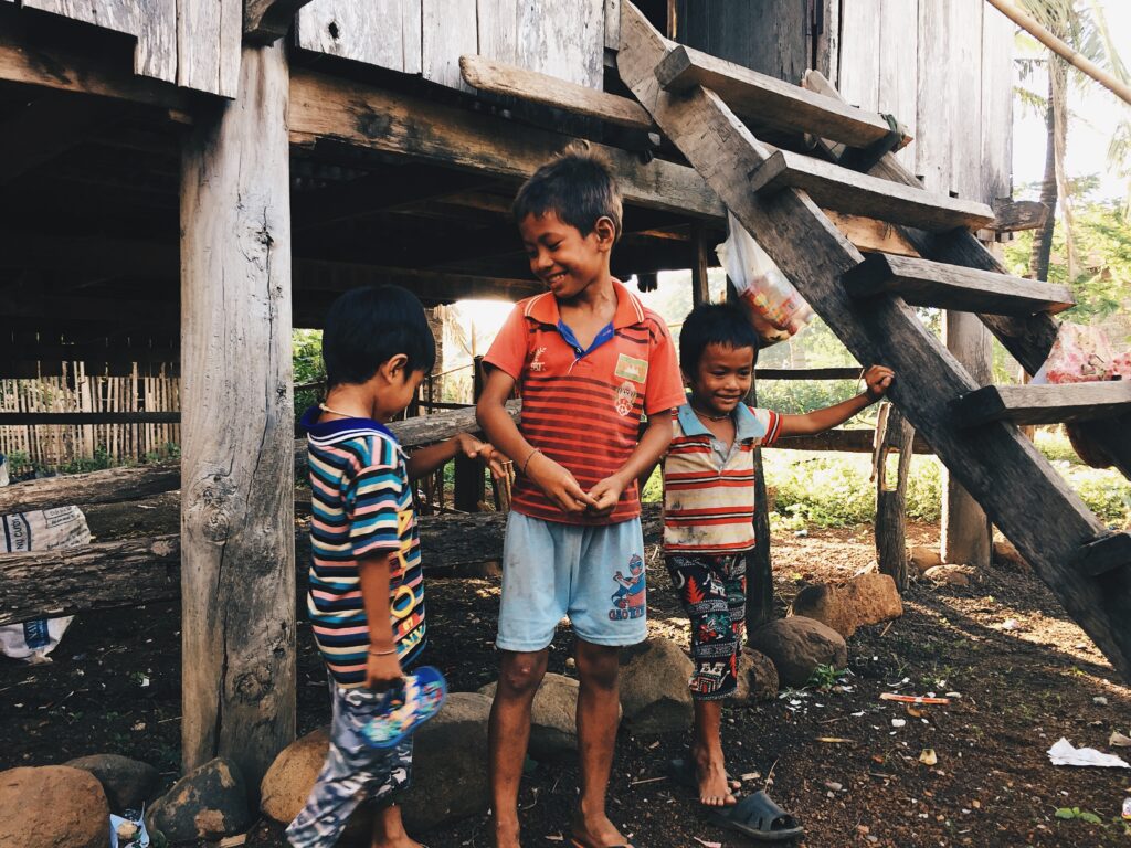 Three boys playing outside in Cambodia. Making connections with the local people is powerful way to heal your life. 