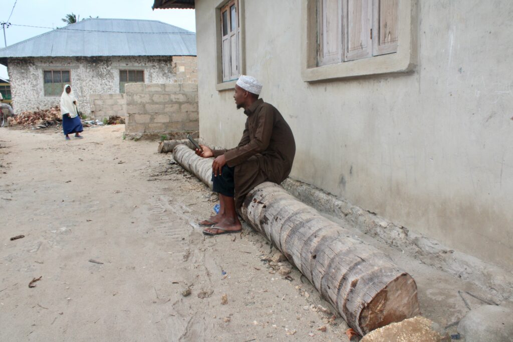 Salum rests on a log in his village where he works as a tour guide